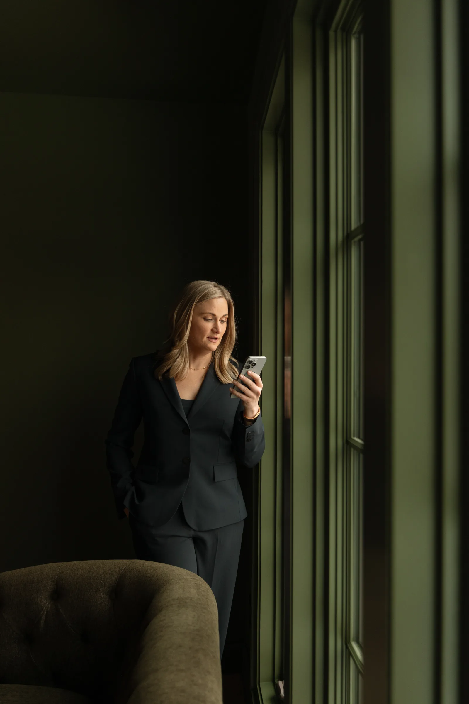 A woman checking her phone beside a window