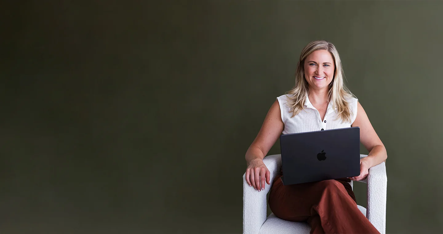 Callan Faulkner, founder of The Uncommon Business, smiling in an armchair with a laptop on her lap.